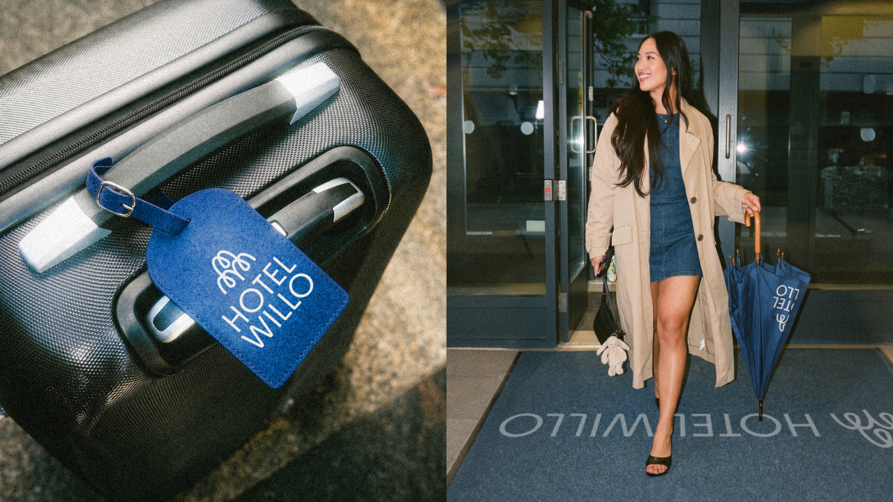Blue luggage tag with Hotel Willo branding on a black suitcase, and woman carrying blue umbrella entering hotel building