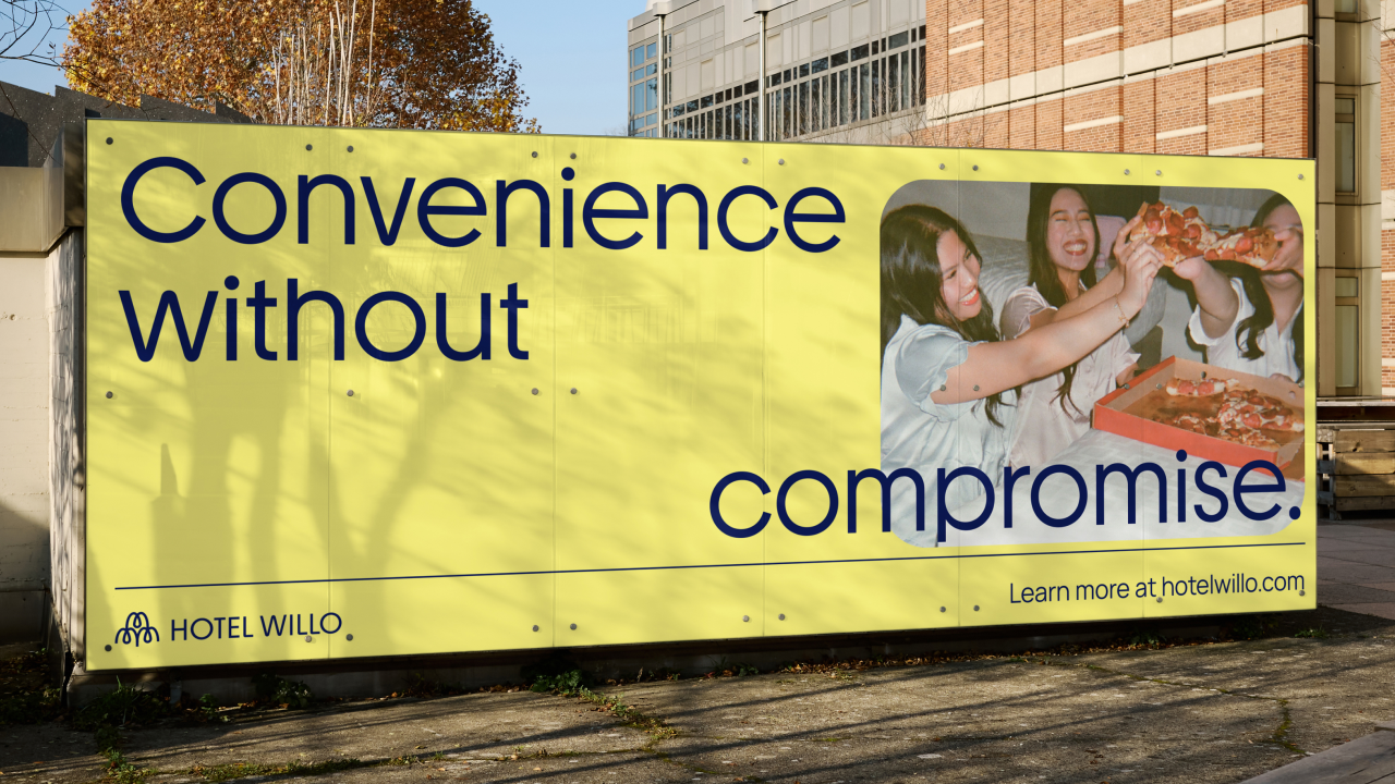 Bright yellow billboard featuring Hotel Willo's "Convenience without compromise" tagline, with a photograph of people enjoying pizza together on the right side