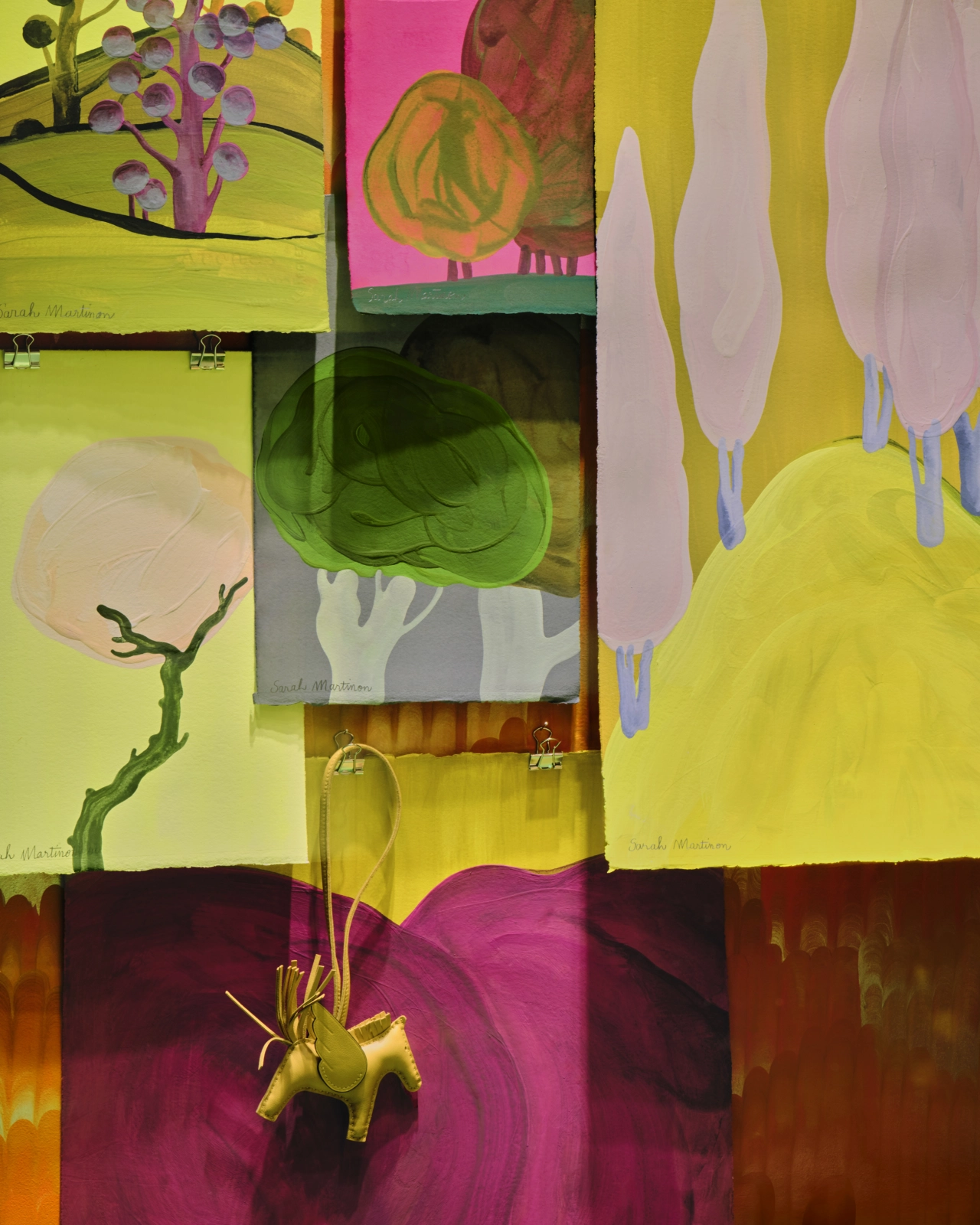 Collage of Sarah Martinon's colourful paintings and drawings featuring botanical forms, branches and organic shapes in yellow, pink and green tones, displayed together as a Hermès window installation.