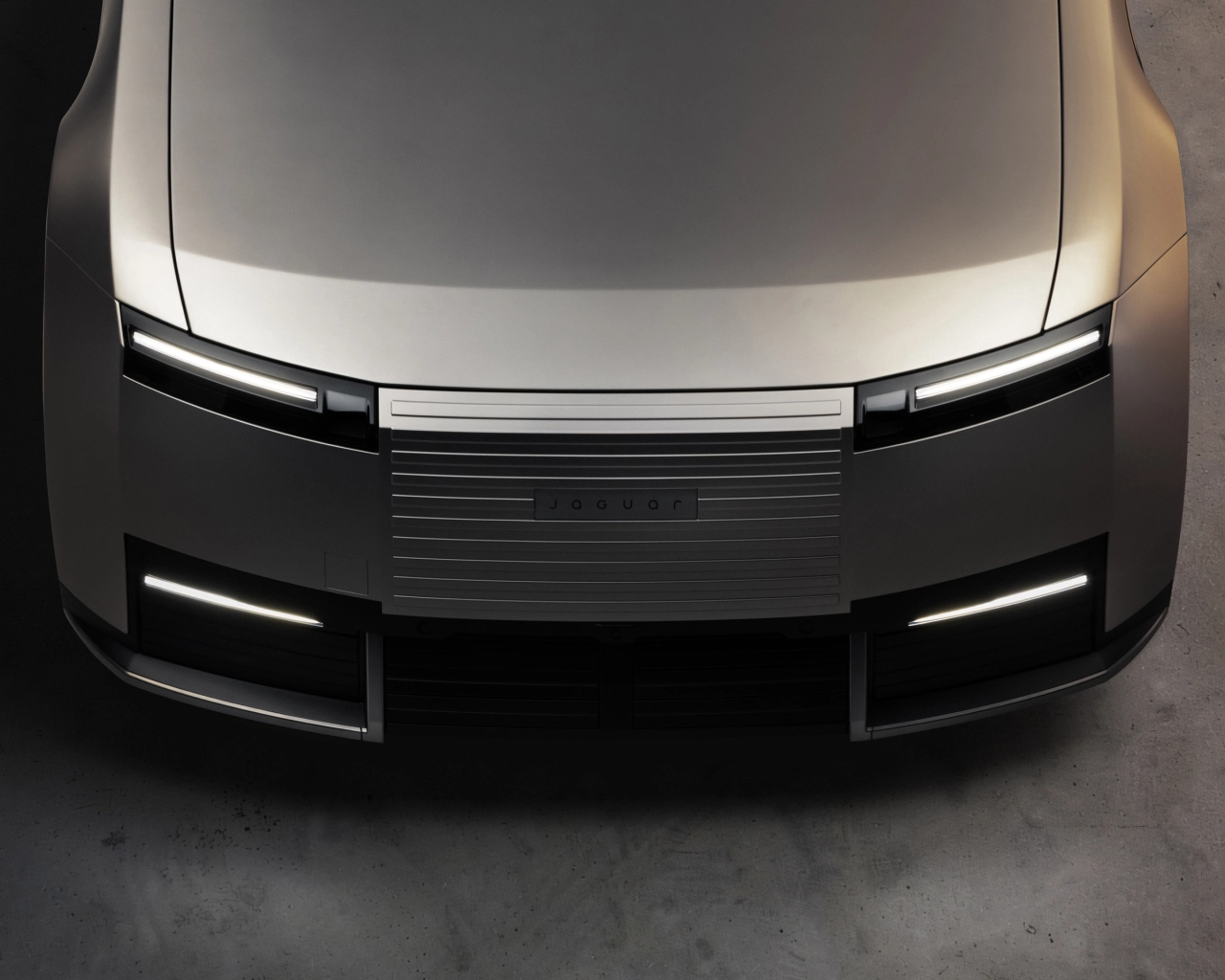 Front view of the Jaguar Type 01 showing its distinctive illuminated headlights and horizontal grille design in silver and black