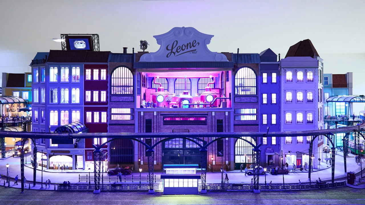 Leone's Happiness Factory facade illuminated in purple and pink neon lights at dusk, with "Leone" signage displayed prominently on the building's roofline